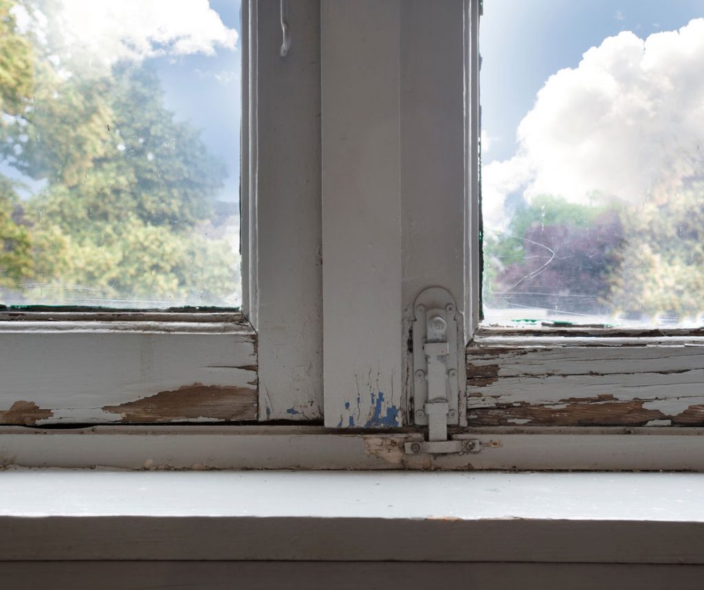 Deteriorating window frame with chipping and peeling paint in a pre-1978 home, a common location where lead-based paint hazards are found in older NYC properties