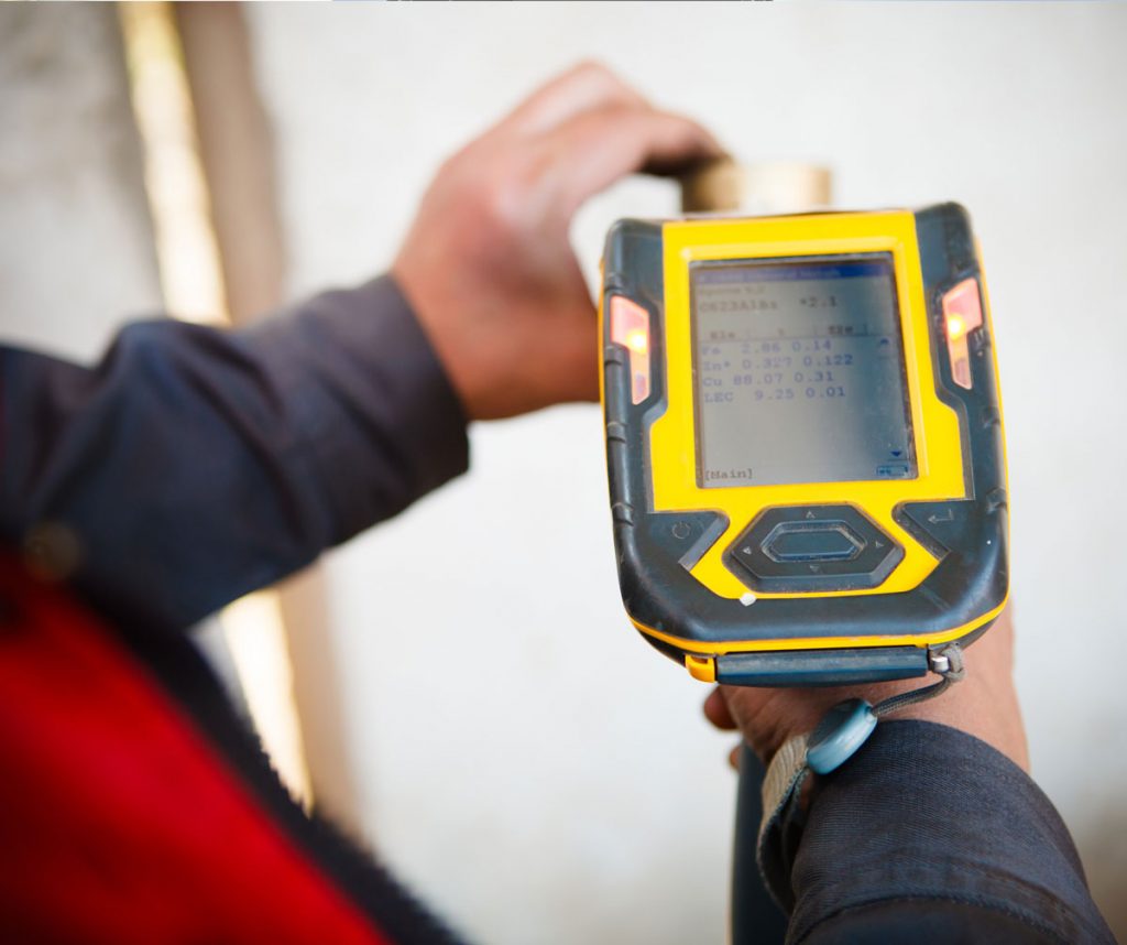 Certified inspector performing XRF lead paint testing on interior wall surfaces in an older building to identify hidden lead-based paint hazards before renovation work.