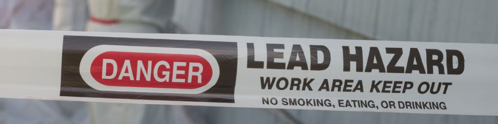 Lead hazard warning barrier marking a restricted work area during lead-based paint testing and environmental risk assessment activities.