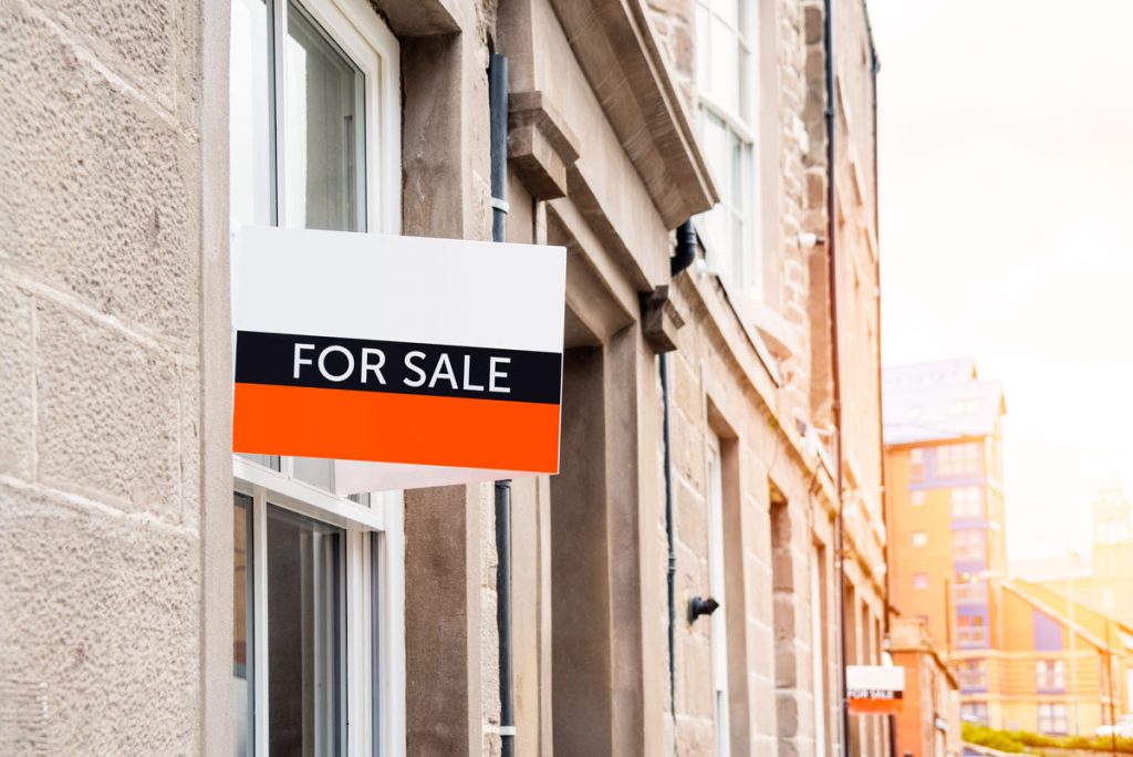 For sale sign outside a residential property illustrating selling a house with violations in NYC